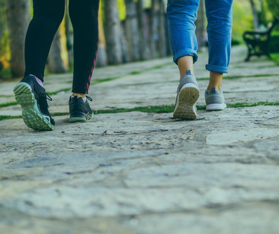 Two people walking on a cobblestone path, focus on their shoes.