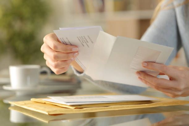 Person opening an envelope over a tray of mail.