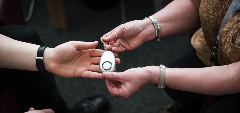 Two people's hands exchanging a small, white electronic device.