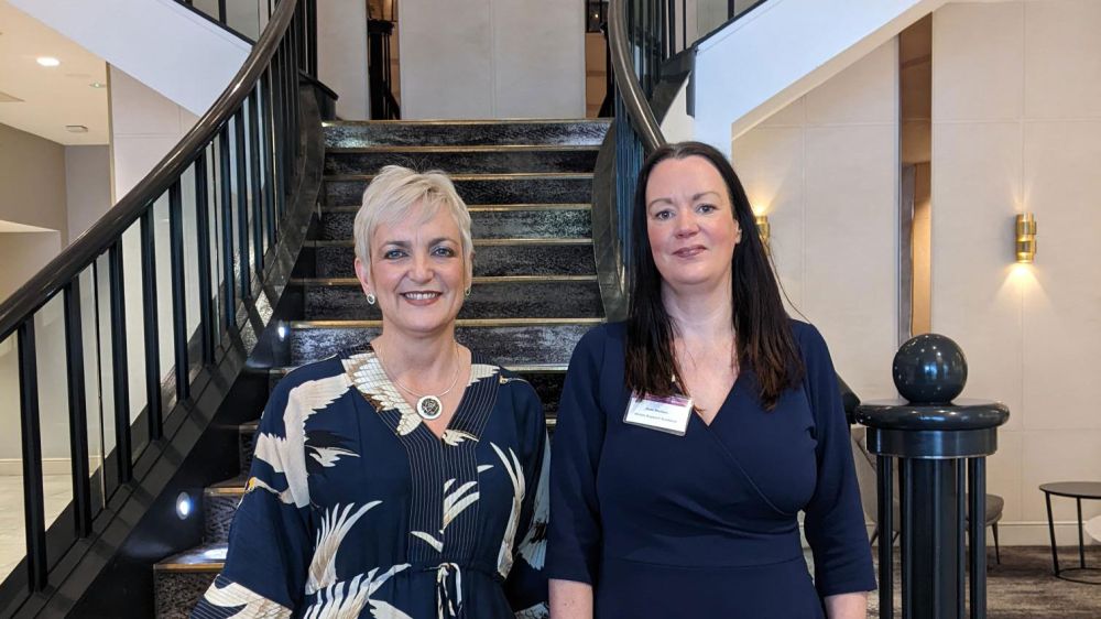 Kate and Angela standing in front of an elegant staircase in a lobby.