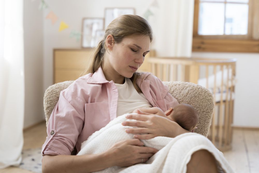 Woman sitting with child and a crib nearby.
