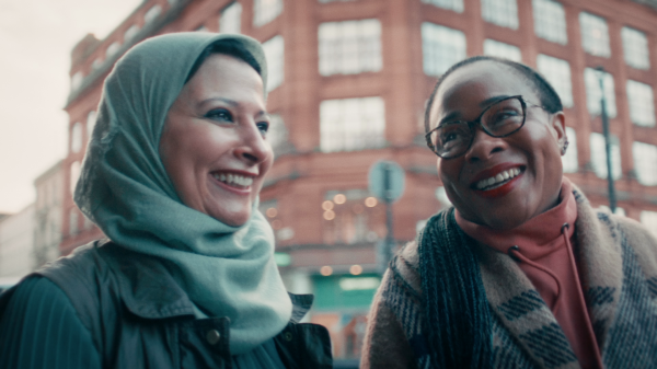Two people in winter clothing with a building in the background.